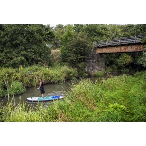 Festkl�dt kvinde paddleborder under den gamle jernbanebro i Lille�en ved Laurbjerg