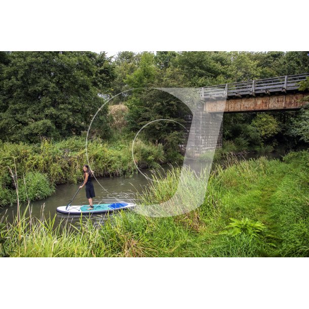 Festkldt kvinde paddleborder under den gamle jernbanebro i Lilleen ved Laurbjerg