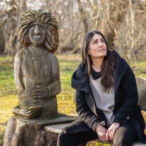 Heidi sider p� en b�nk i Lang� Egeskov, foran flot udsk�ret trold