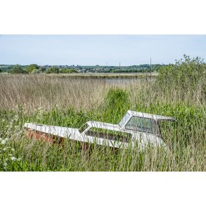 Forladt motorb�d p� sydsiden af Randers Fjord med Dronningborg i baggrunden